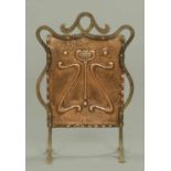 An Art Nouveau copper and ironwork fire screen, of shaped outline.  Width 21 ins.