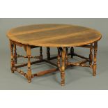 A large oak double gate leg dining table, oval in plan.  Width 181 cm, length open 201 cm.