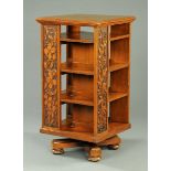 A late Victorian walnut revolving bookcase, with foliate carved panels.  Width 56.5 cm.