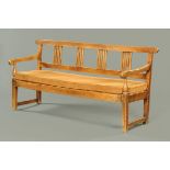 A 19th century farmhouse oak settle, with slatted back, squab cushion over webbing and raised on