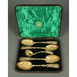 Four late Victorian gilt white metal berry spoons and one sifting spoon, cased.