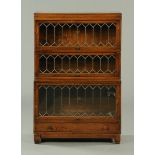 An oak sectional bookcase, Globe Wernicke, three tier, with lead glazed doors and low drawer.  Width