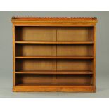 A late Victorian walnut open bookshelf, with fretwork gallery,