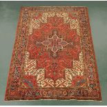 An Iranian woollen rug, fringed, principal colours red,beige and black.