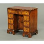 * A George I style walnut kneehole desk, with red gilt tooled writing surface, moulded edge,