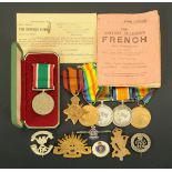 A collection of World War One medals, cap badges, Women's Volunteer Service medal, etc., contained