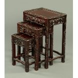 An early 20th century nest of three Chinese hardwood tables, typical form, foliate carved.