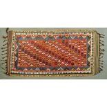 * A large Kelim rug, the centre rectangular panel with red ground and repeating motifs and with