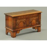 A small oak coffer, Chapmans Siesta, with double arch carved front and raised on bracket feet.