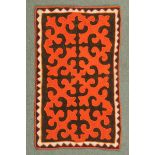 * A small floor felt, rectangular, with brown ground and repeating design in bright orange.