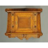 An Arts & Crafts oak hanging corner cupboard, with single door flanked by flat pilasters.  Width