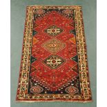 An Iranian woollen fringed rug, principal colours red, blue, black and beige.