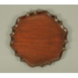 An Edwardian mahogany tray, with piecrust moulded edge.  Diameter approximately 38 cm.  CONDITION