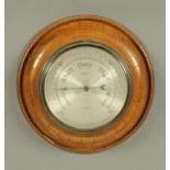 A Kendal & Dent London oak cased aneroid barometer, circa 1930.  Diameter 28 cm.