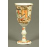 A Japanese Arita cup, with knopped stem and decorated with figures and buildings.  Height 15.4 cm.