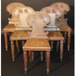 A set of five early 19th Century oak panel seated hall chairs, the C scroll decorated backs with