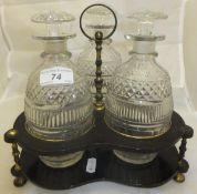 A set of three early 19th Century  cut glass decanters on an ebonised wood and brass stand CONDITION