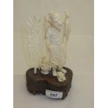An early 20th Century carved ivory figure depicting a Japanese fisherman holding a fish aloft beside