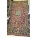 A Kashan rug, the central panel set with floral decorated medallion on a red ground with floral