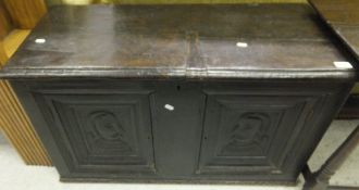 A 16th Century style oak coffer, the plain top above a pair of panels depicting portrait of a