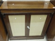 An early Victorian rosewood side cabinet, the plain top above two glazed panelled doors on a