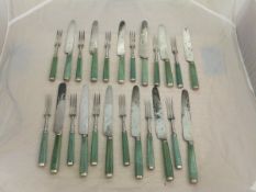 A set of twelve 19th Century stained green ivory handled knives and forks with white metal mounts,