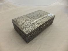 An Eastern embossed white metal cigarette box with fitted interior, the exterior decorated with