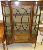An Edwardian mahogany and inlaid display cabinet, the central glazed door flanked by two bowed