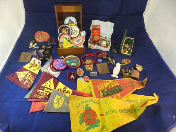 A box containing assorted pin badges, cloth badges, pennant flags, etc, related to the Girl Guides