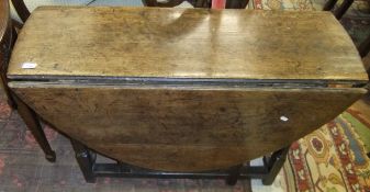 An 18th Century oak oval gate-leg drop-leaf dining table on turned supports to block feet united