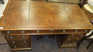 A mahogany pedestal desk of nine drawers with brass loop handles and escutcheon and brown tooled