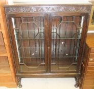 A 1920's oak display cabinet with carved