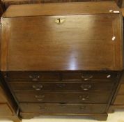An 18th Century oak bureau, the sloping fall enclosing a stepped fitted interior with various