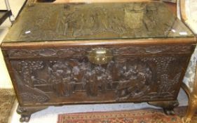 A carved camphor wood chest depicting figures within an interior, raised on paw feet CONDITION