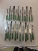 A set of twelve 19th Century stained green ivory handled knives and forks with white metal mounts,