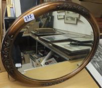 An oval bevel edged mirror in a brass ef