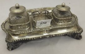 A George III silver inkstand with applied gadrooned edge, raised on four scroll feet (by Edward