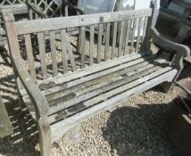 A weathered hardwood three seater bench with plaque inscribed "Built from timber ex HMS Defiance