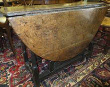 An 18th Century oak oval gate-leg drop-leaf dining table on turned supports to block feet united