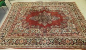 A Persian carpet, the central floral decorated medallion in shades of pale red, cream,