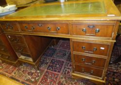 A reproduction yew wood veneered pedestal desk with a rectangular top with leather insert and