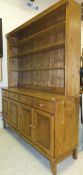 A modern pine dresser of four open shelves above four short drawers and four cupboard doors with