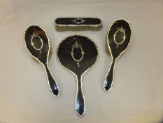 A silver and tortoiseshell mounted dressing table brush set comprising hand mirror and three