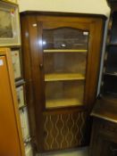 A retro mahogany corner cabinet with glazed cupboard door opening to reveal three beech shelves