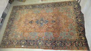 A Persian rug, the central medallion in dark blue, pink, yellow and pale green on an apricot