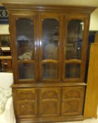 An oak display cabinet with three glazed doors enclosing shelves on a base of two cupboard doors