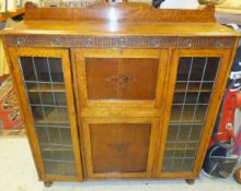 An oak secretaire cabinet with leaded glazed doors and writing compartment above single door