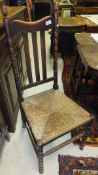 A set of six early 20th Century oak slat back rush seat dining chairs on bobbin turned supports (4