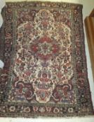 A Persian rug, the central medallion in dark red, pink, cream and green,