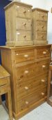 A modern pine tall chest of two short and three long drawers on a plinth base with turned knob